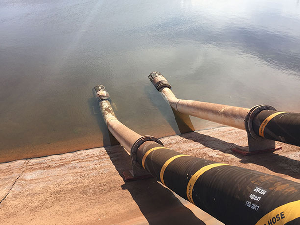 Two infrastructure pipelines resting beside a river.