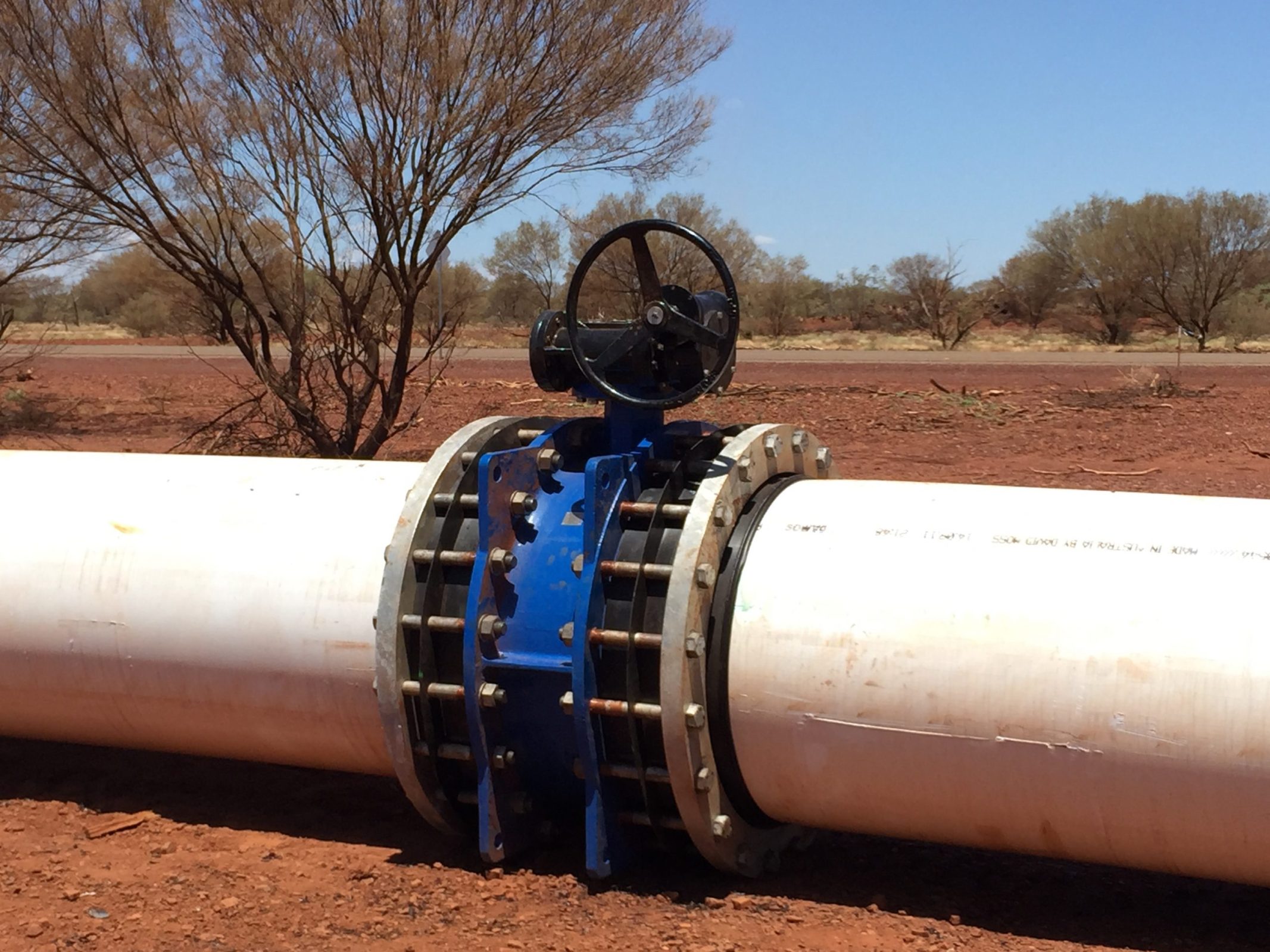 A large infrastructure pipeline with a blue and white valve attached.