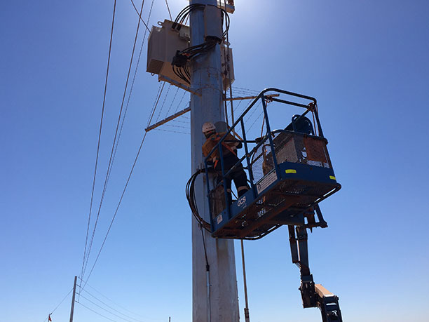 A worker on a lift repairing a power pole as part of the infrastructure pipeline.